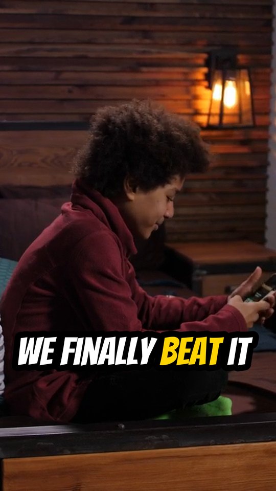 A vertical 9:16 clip of a teen gaming on his phone, captioned WE FINALLY BEAT IT
